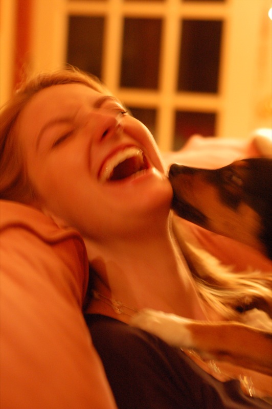 Puppy licking laughing woman
