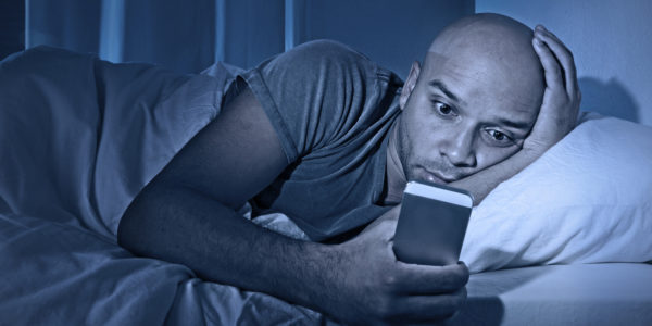 man looking at phone in bed