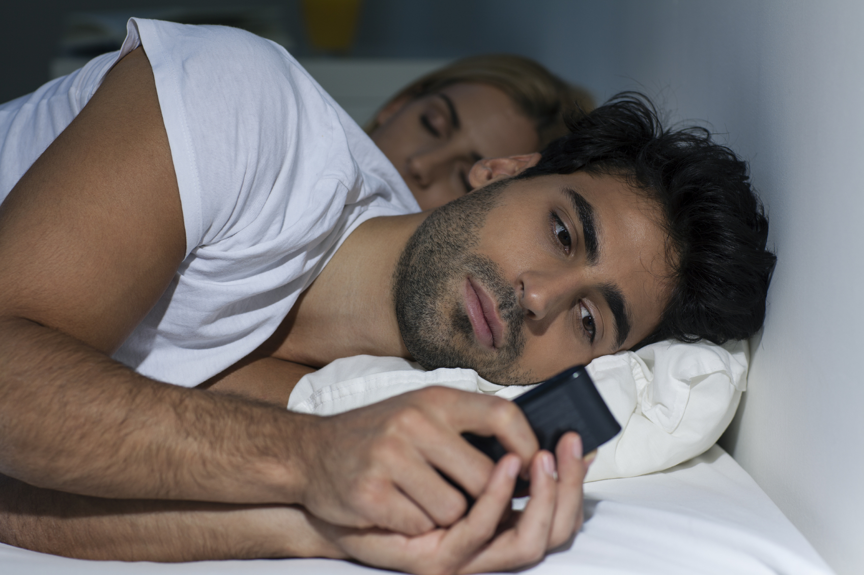 man checking phone in bed